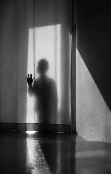 Figura dietro una tenda con la mano appoggiata al tessuto, bianco e nero